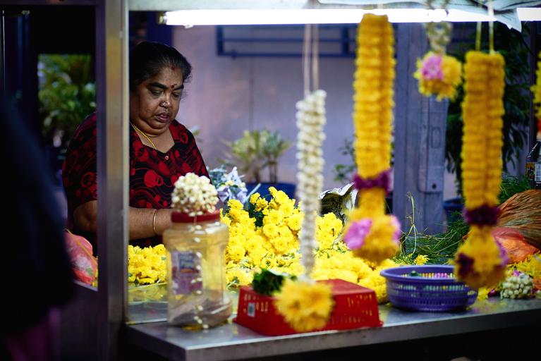 žena, která dekoruje z květin žlutých nějakou vazbu u stojanu, kolem jsou květiny